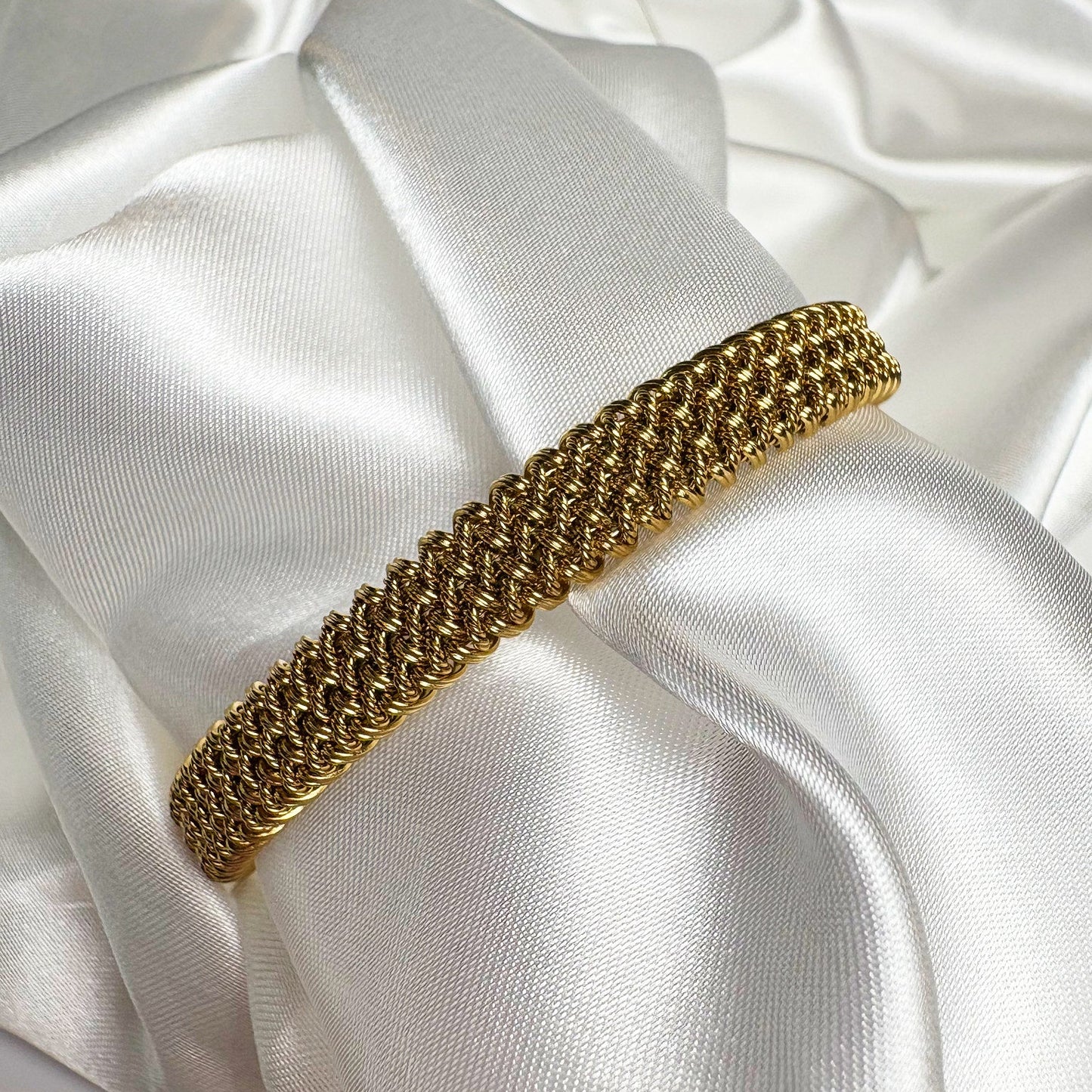 Gold bracelet on a white satin surface
