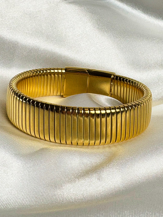 Gold bracelet on a white fabric background