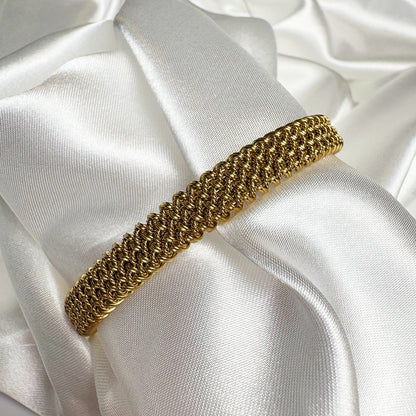 Gold bracelet on a white satin surface