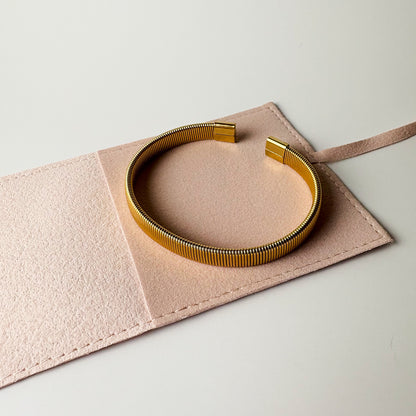 Gold necklace on a pink jewelry box with a light gray background
