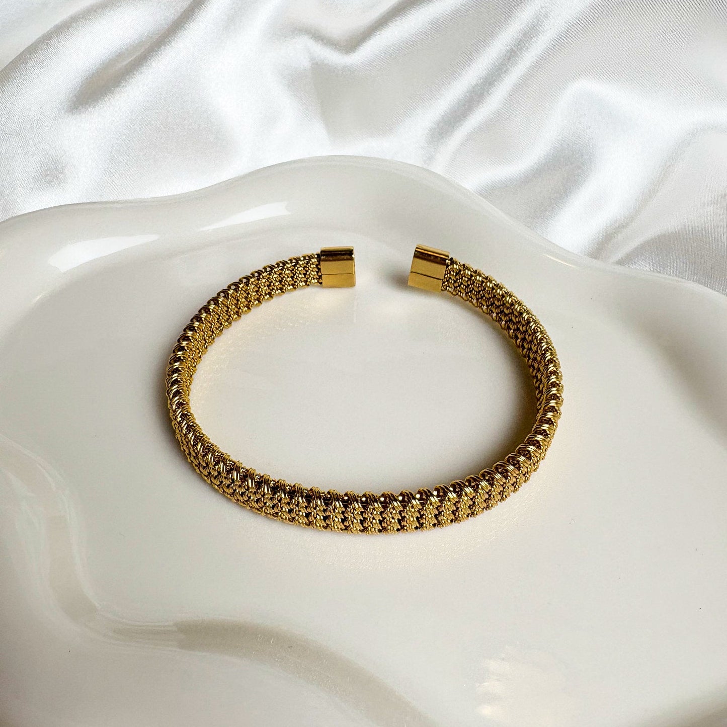 Gold bracelet on a white, textured surface