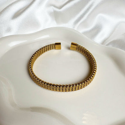 Gold bracelet on a white, textured surface