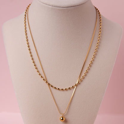 Gold necklace on a mannequin bust with a pink background