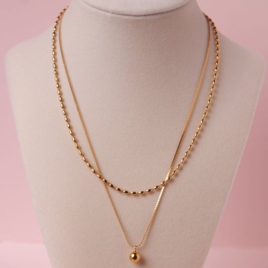 Gold necklace on a mannequin bust with a pink background