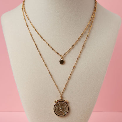 Gold necklace with a pendant on a mannequin bust against a pink background