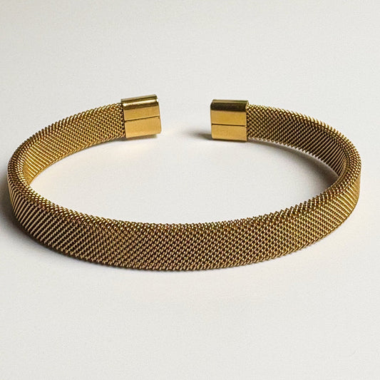 Gold mesh bracelet on a light gray background